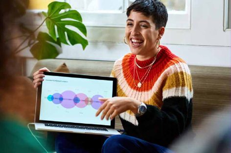 Woman laughing while presenting a chart on her laptop screen to a colleague